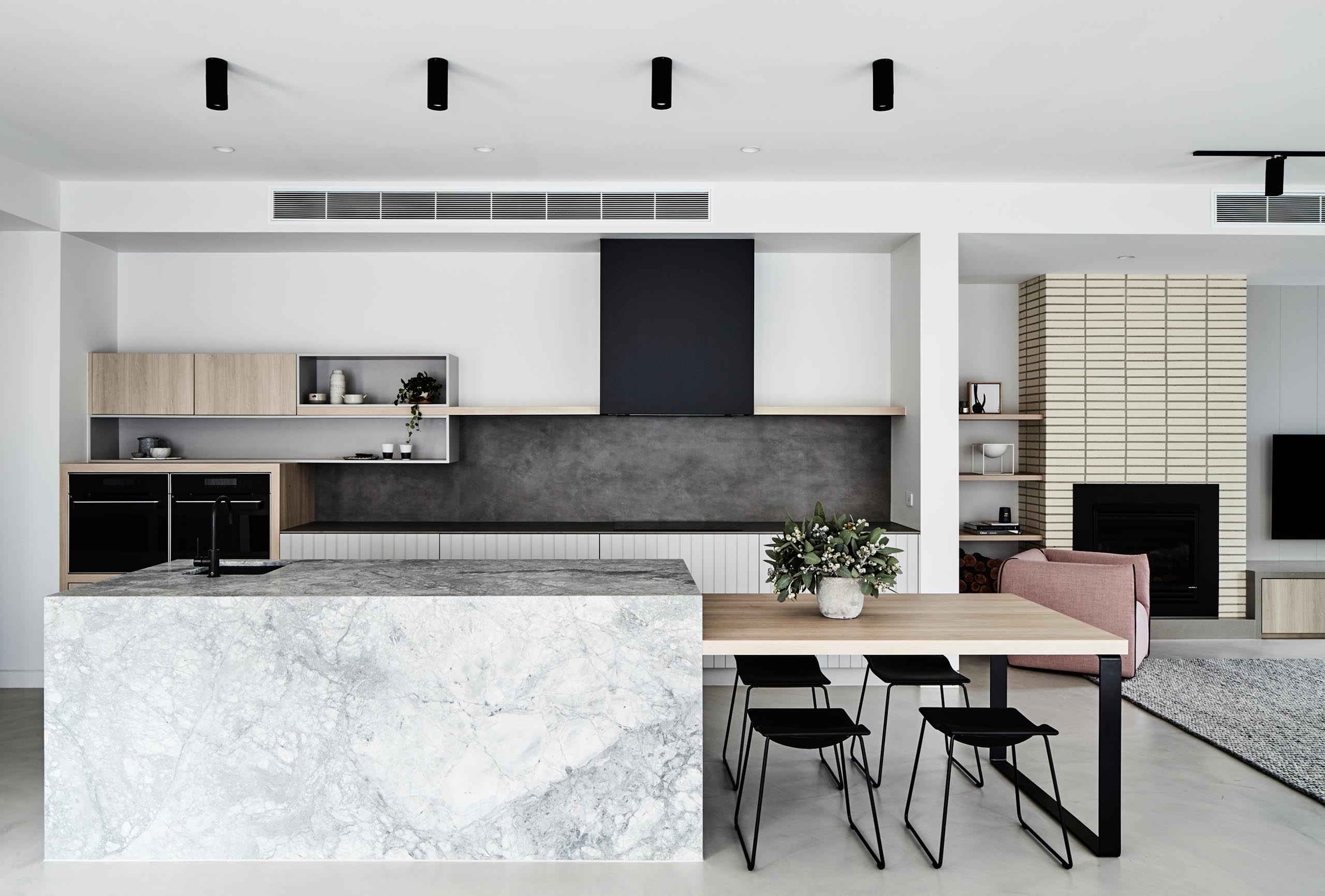 Modern kitchen and dining area with marble island and black chairs.